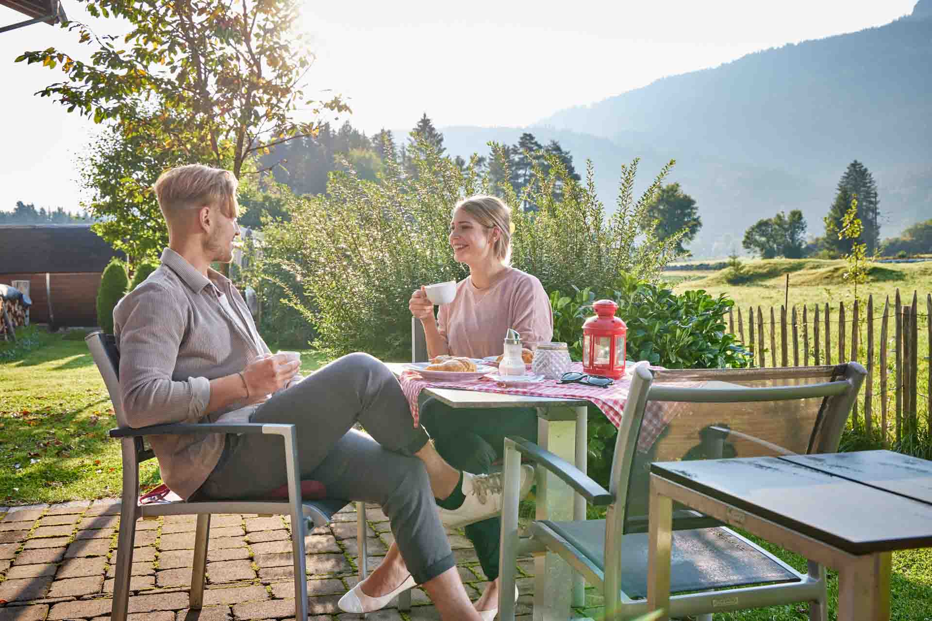 Camping-Erlebnis in Grainau. Paar sitzt an Tisch an unseren Berghütten.