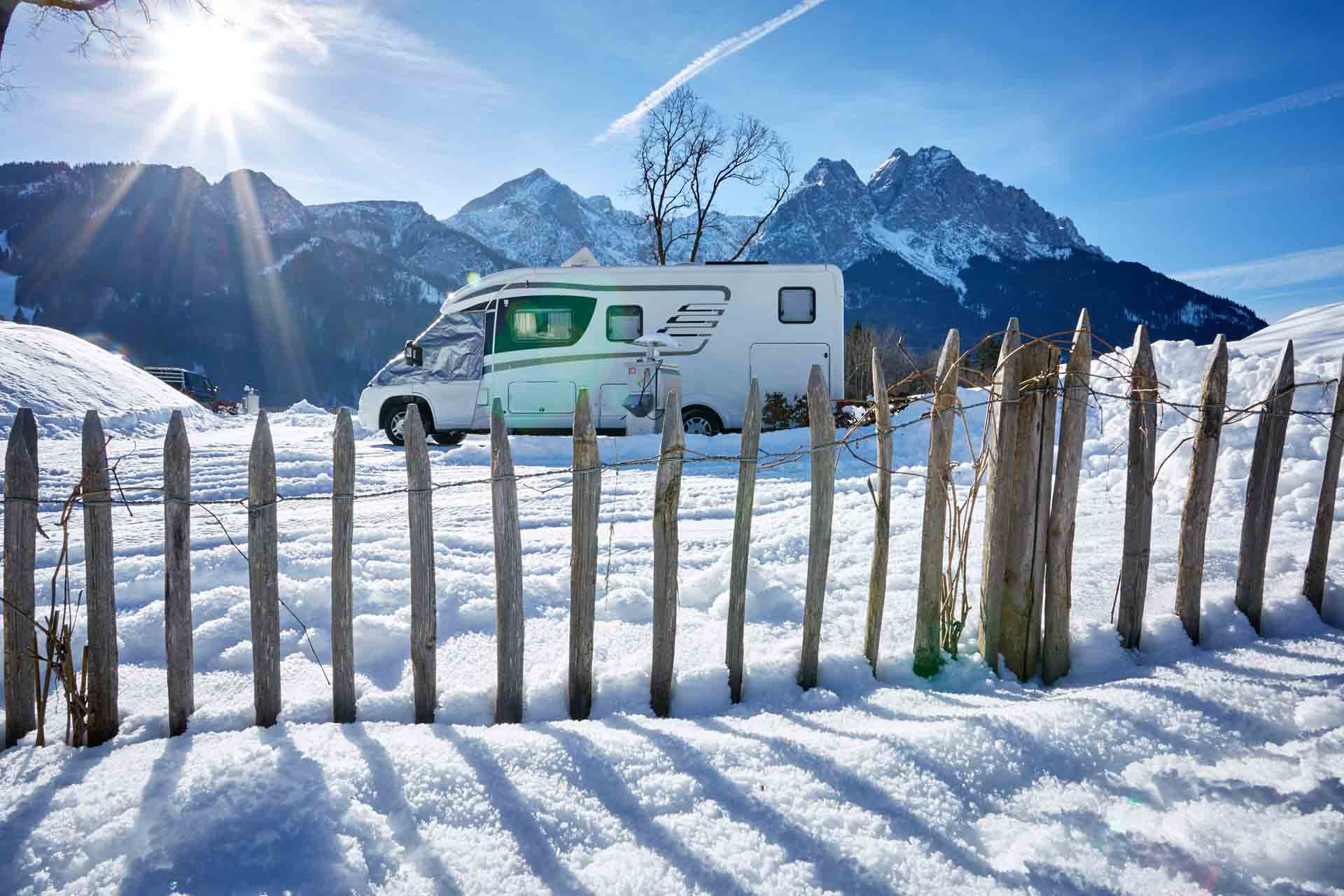 Camping-Erlebnis in Grainau. Ein Wohnmobil vor winterlicher Kulisse mit Zugspitze im Hintergrund.